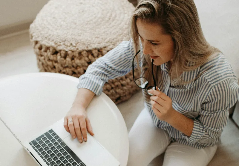 Frau mit Laptop, sitzt, Brille, nachdenklich.